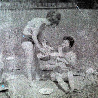 Three children playing outdoors with frisbees and toys.