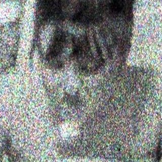 Here's a brief summary of the image: Two children sit in chairs in a grassy, blurred area.