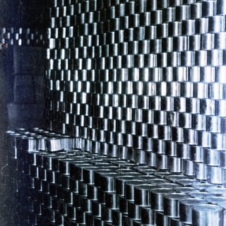 Stacked rows of canned goods fill a darkened storage space.