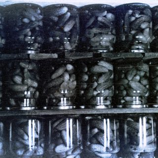 Black and white image of jars filled with pickles.