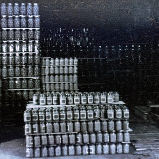 Stacked crates of glass bottles in a darkened warehouse.