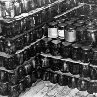 Stacked jars fill shelves in a darkened storage area.
