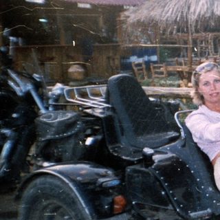 Person sits on a trike in front of a tiki bar.