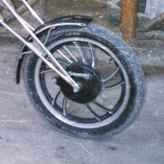 Person sits on a trike in front of a tiki bar.