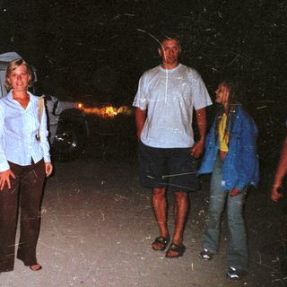 People standing near a camper van at night.