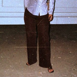 Woman stands next to a stretch limousine at night.