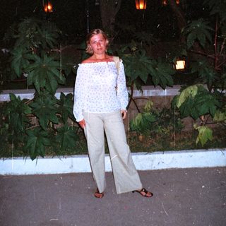 Woman stands outdoors at night, lit by lanterns.