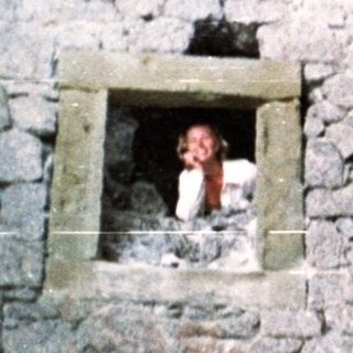 Stone structure with a person inside and one outside.