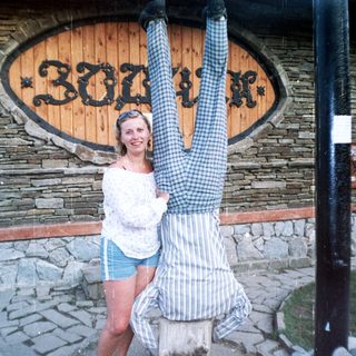 Woman smiles while a man hangs upside down from a tree.