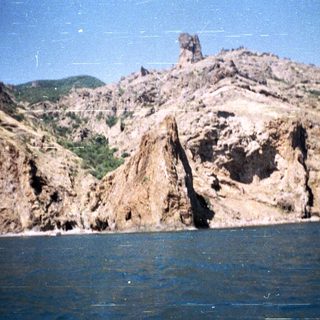 Dramatic rock formations rise from the shoreline and sea.