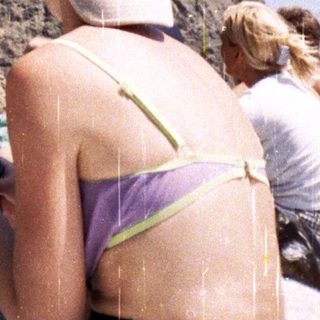 Person on boat looks at phone with mountain backdrop.