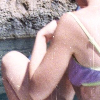 Person floats on water near a rock cliff face.