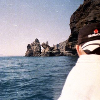 Person looking out at rocky coastline over the ocean.