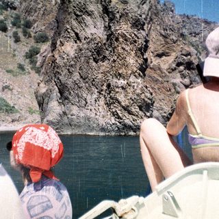 People in a boat view a rocky cliff face.