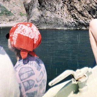 People in a boat view a rocky cliff face.