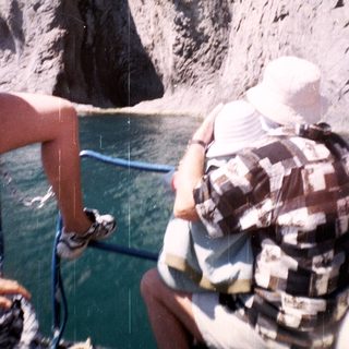 Person on boat observes a tall, rocky cliff face.