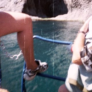 Person on boat observes a tall, rocky cliff face.