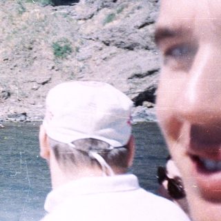 People on a boat photograph a rocky cliff face.