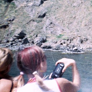 People on a boat photograph a rocky cliff face.