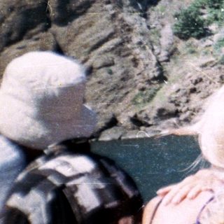 People view a river with steep, rocky cliffs.