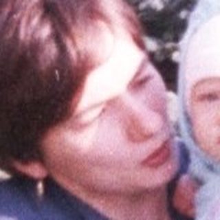 Woman holds baby amongst a field of young pine trees.