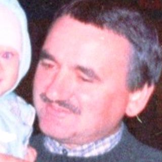 Man holding a baby outside a building at night.