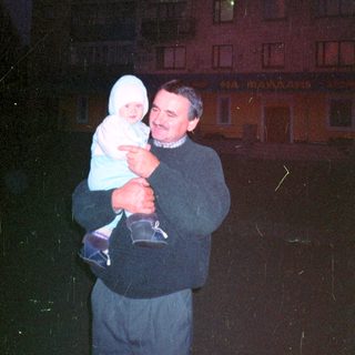 Man holding a baby outside a building at night.