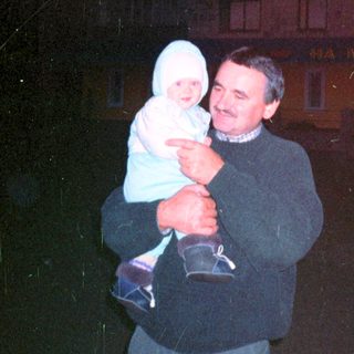 Man holding a baby outside a building at night.