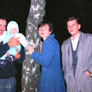Family posing outdoors near a tree at night.