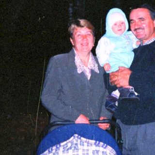 Man and woman holding baby, standing near a stroller.