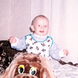 Baby sits on a large dog toy with balls nearby.