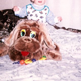Baby sits on a large dog toy with balls nearby.