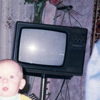 Baby sits in a high chair in a vintage room.