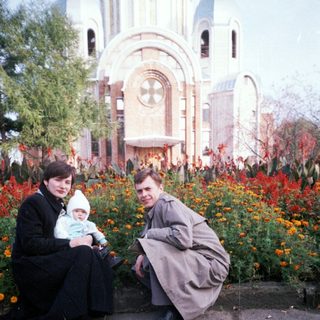 Family poses outdoors in front of an ornate building.
