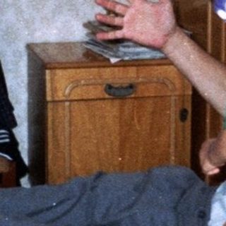 A boy jumps on a bed while others watch.