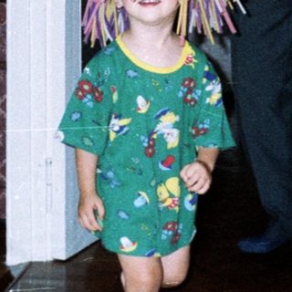 Here's a brief summary of the image: Child with a wig runs, followed by an adult.