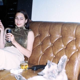 Woman and cat relax on a tufted, leather couch.