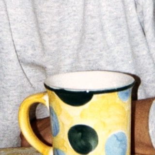 Here's a brief summary of the image: Older woman with short hair, touching her eye.