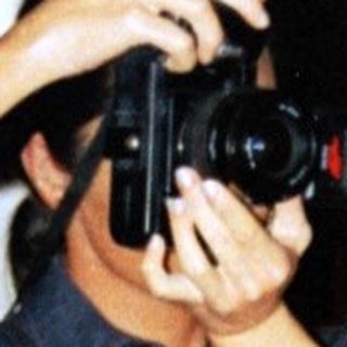 Person takes a photo outside at night near a tree.