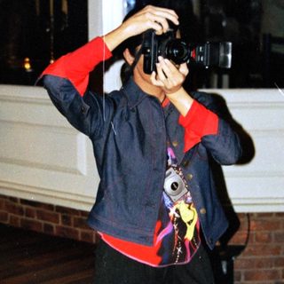 Person takes a photo outside at night near a tree.