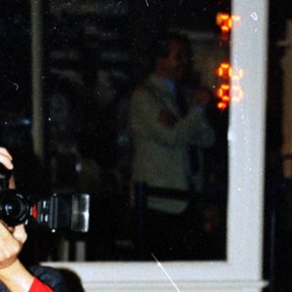 Person takes a photo outside at night near a tree.
