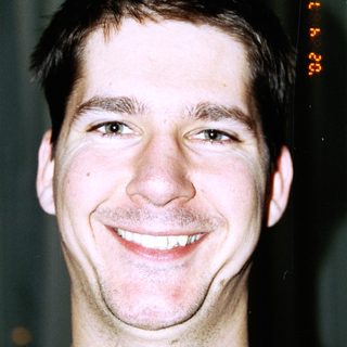 Here's a brief summary: Smiling man with short hair and a blue shirt.