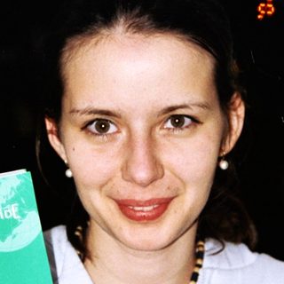 Woman holds up a "Green Guide" travel book about Sicily.
