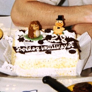 Man stands next to a birthday cake with decorations.