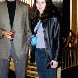 Man and woman standing near an ornate staircase and elevator.