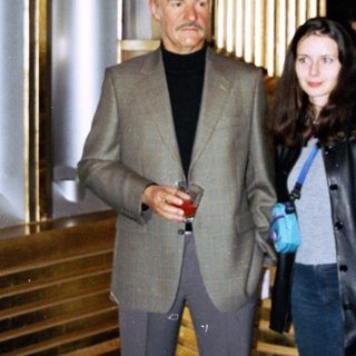 Man and woman standing near an ornate staircase and elevator.