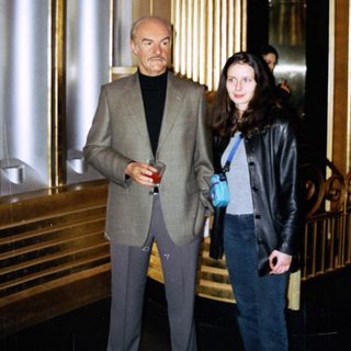 Man and woman standing near an ornate staircase and elevator.