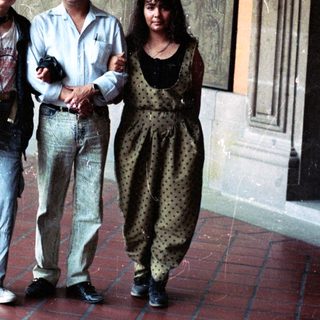 People pose near a mural in a building hallway.