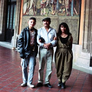 People pose near a mural in a building hallway.