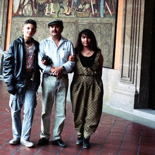 People pose near a mural in a building hallway.
